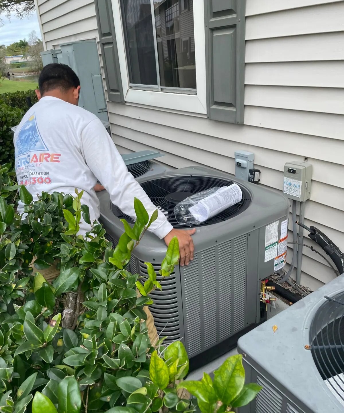 Iceberg Aire technician servicing an outdoor AC condenser at a Southwest Florida home
